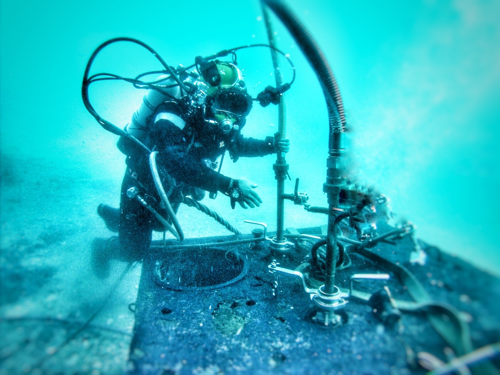 Adiestramiento de buzos conectando mangueras de ventilación sobre simulador de submarino.